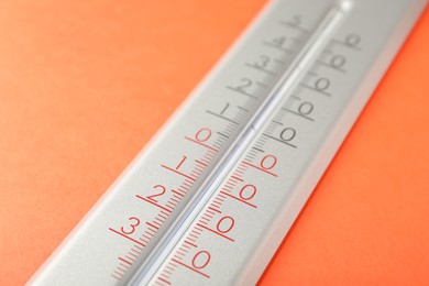 Photo of Modern weather thermometer on orange background, closeup