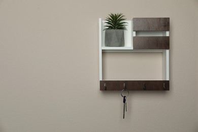 Photo of Wooden key holder on beige wall. Space for text