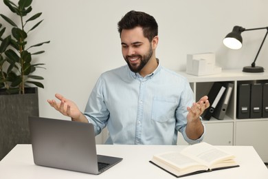 Photo of Young man having video chat via laptop at table indoors