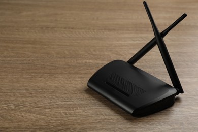 Photo of Modern Wi-Fi router on wooden background. Space for text