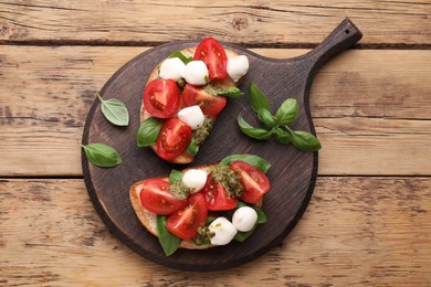 Photo of Delicious Caprese sandwiches with mozzarella, tomatoes, basil and pesto sauce on wooden table, top view