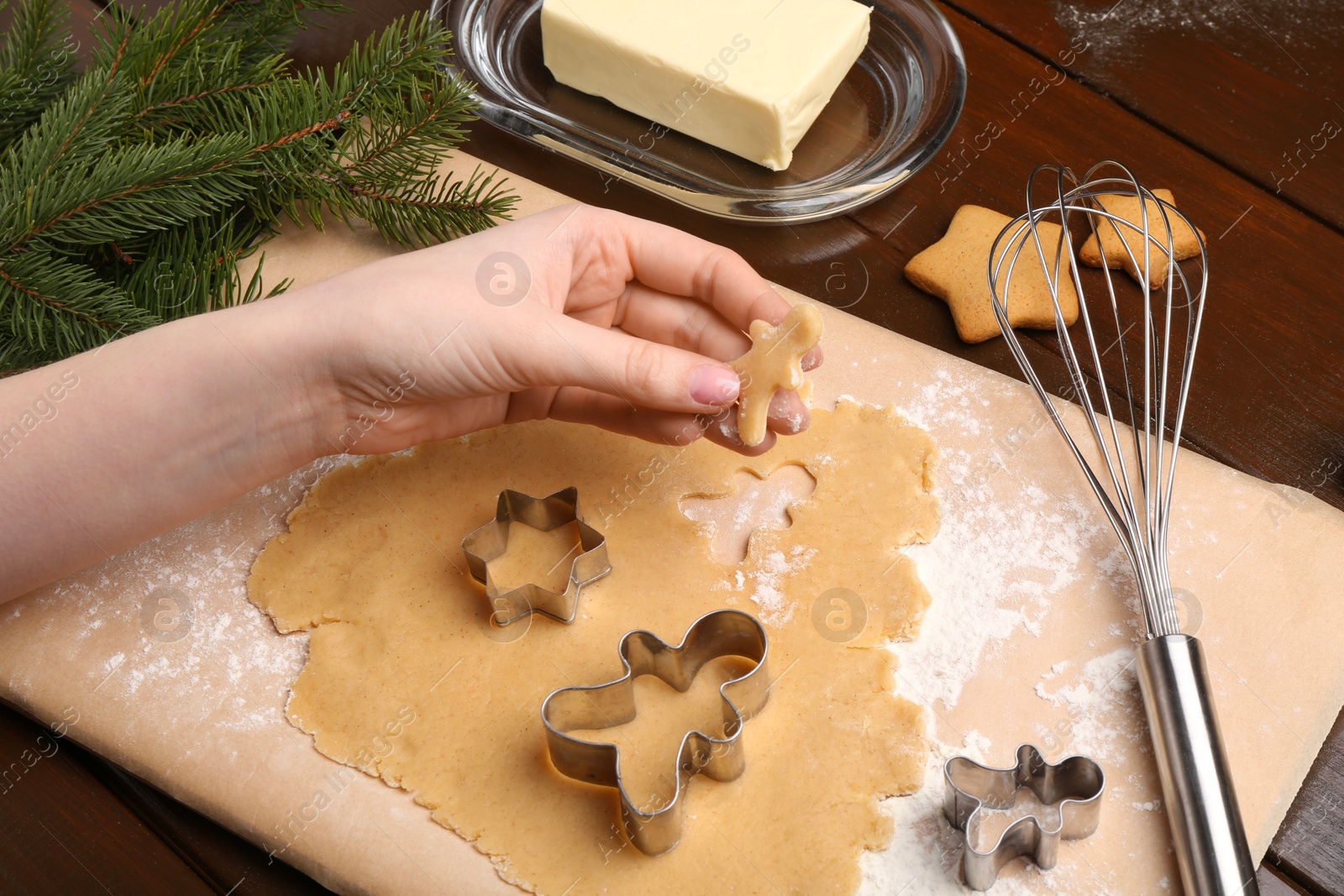 Photo of Woman making Christmas cookies with cutters at wooden table, closeup