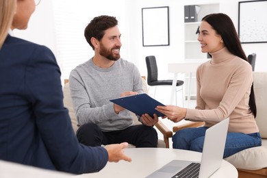 Photo of Couple signing contract in real estate agent's office