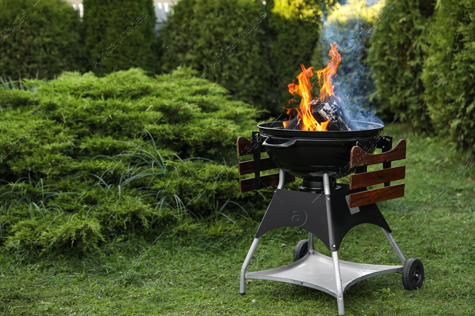 Photo of Portable barbecue grill with fire flames outdoors. Space for text