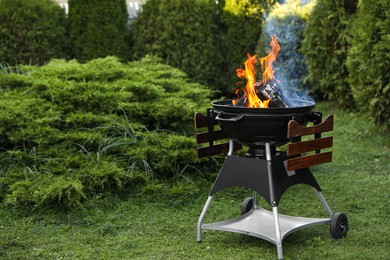 Photo of Portable barbecue grill with fire flames outdoors. Space for text