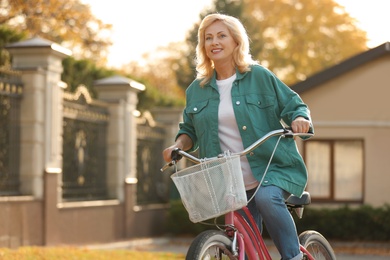 Photo of Mature woman riding bicycle outdoors. Active lifestyle