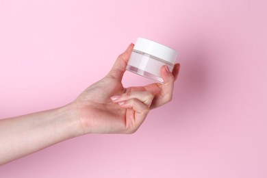 Photo of Woman holding jar of cream on pink background, closeup
