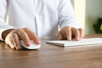 Photo of Man using computer mouse and keyboard at table, closeup