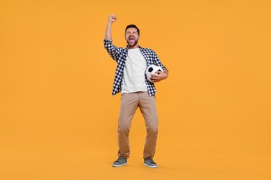 Photo of Emotional sports fan with ball celebrating on yellow background