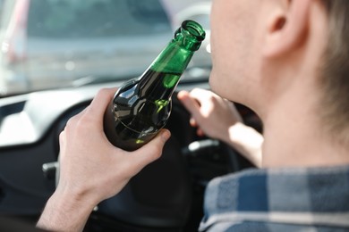 Photo of Man with bottle of beer driving car, closeup. Don't drink and drive concept