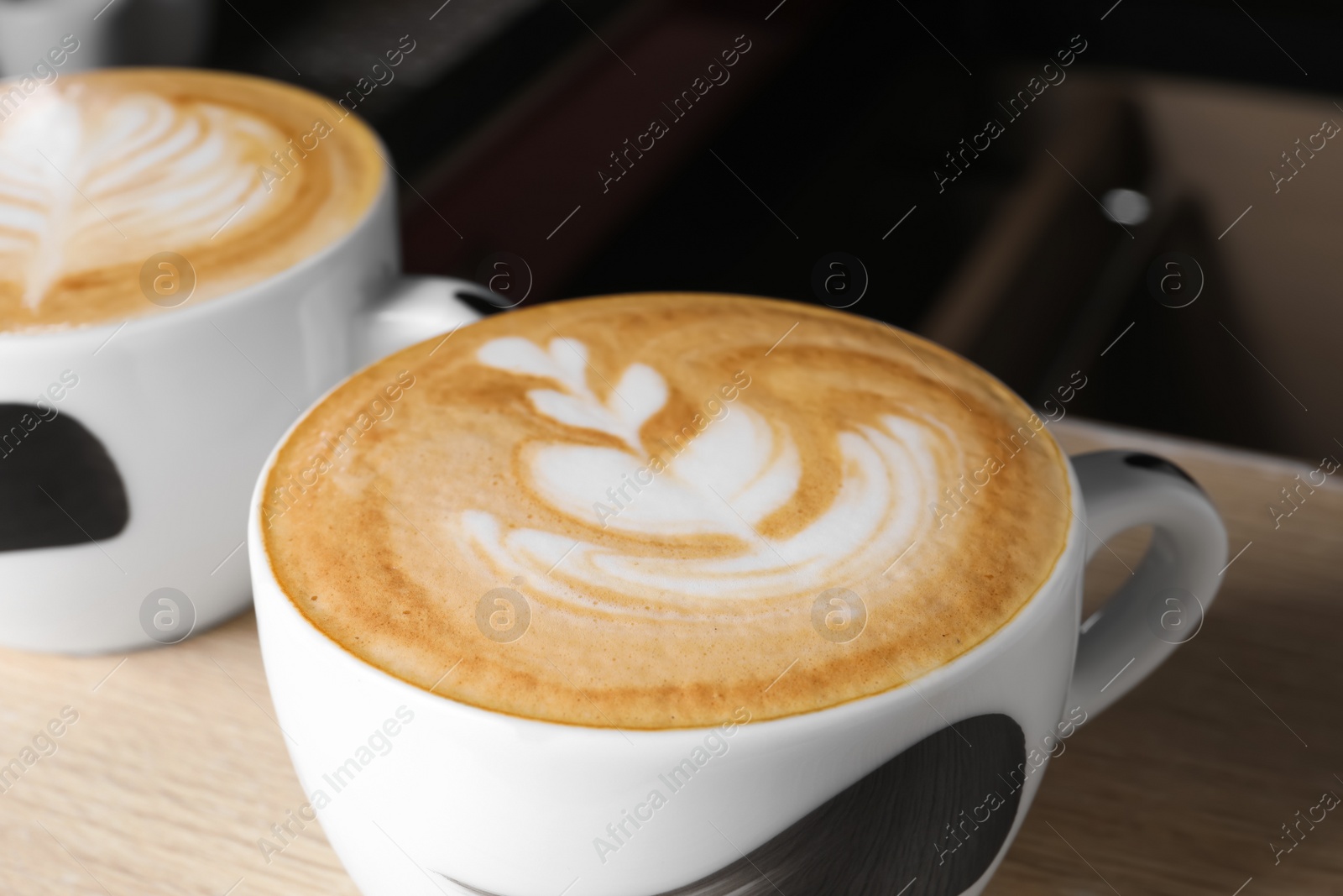 Photo of Cups of fresh aromatic coffee on table in cafe, closeup