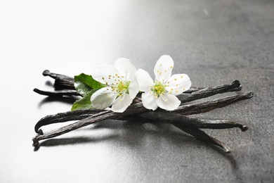 Photo of Vanilla sticks and flowers on grey background