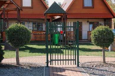 Photo of Closed metal gates near beautiful houses and playground
