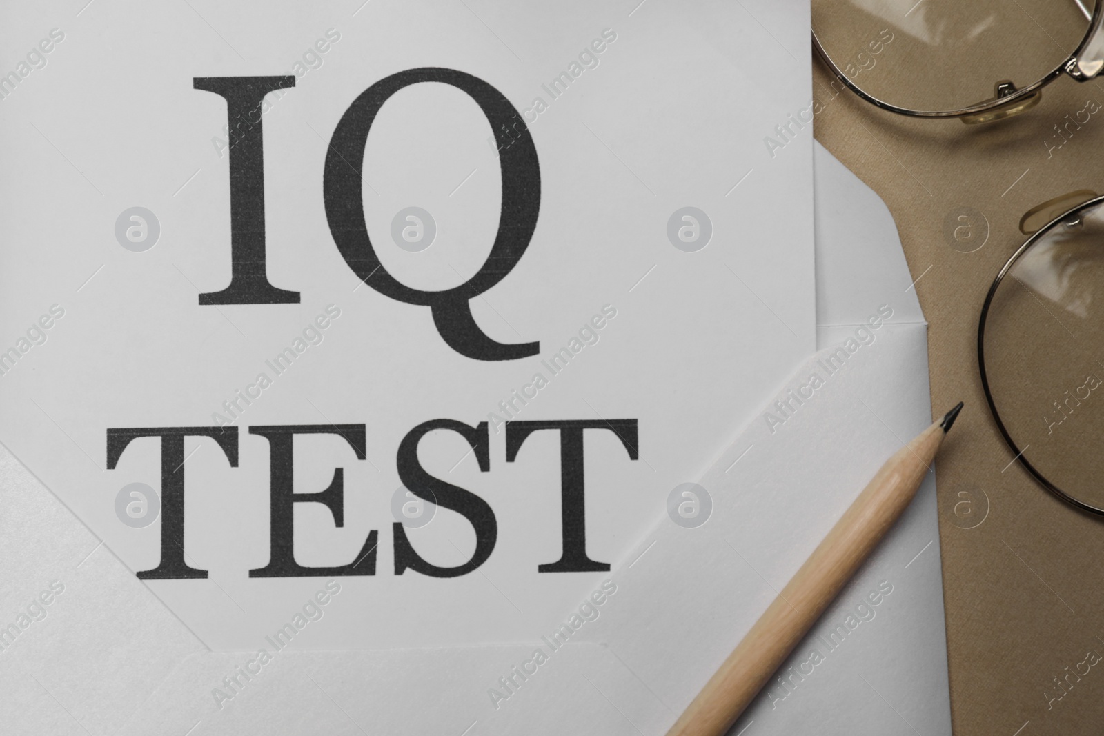 Photo of Paper with words IQ Test in envelope and pencil on notebook, flat lay