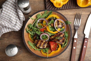 Photo of Delicious salad with roasted eggplant and arugula served on wooden table, flat lay