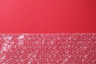 Photo of Transparent bubble wrap on red background, top view. Space for text