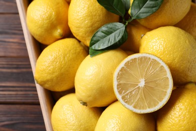 Fresh lemons in crate on wooden table, top view