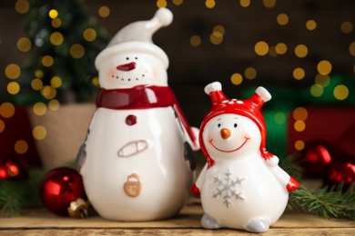 Photo of Cute little snowmen and Christmas decor on wooden table