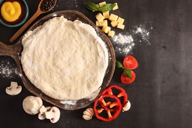 Photo of Pizza dough and products on dark table, flat lay. Space for text