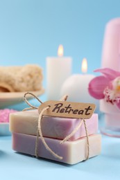 Photo of Retreat concept. Soap bars tied with rope and card on light blue background, closeup