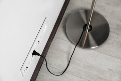 Photo of Floor lamp plugged into wall power socket indoors, above view