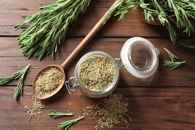 Photo of Jar with dried rosemary and twigs on wooden table, top view