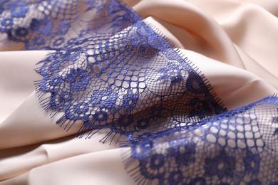 Photo of Beautiful blue lace on beige fabric, closeup