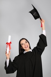 Photo of Happy student with graduation hat and diploma on grey background