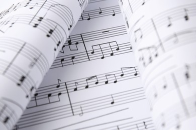 Photo of Sheets of paper with music notes as background, closeup view