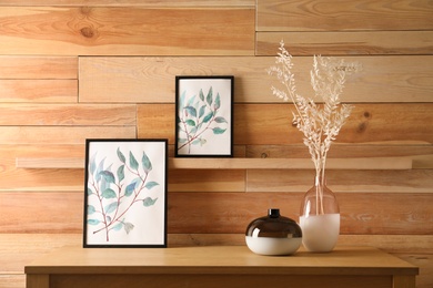 Photo of Decorative vases and pictures on wooden table
