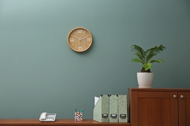 Photo of Office interior with houseplant and clock on wall. Time management