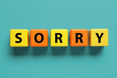 Image of Apology. Word Sorry made of colorful cubes on turquoise background, top view