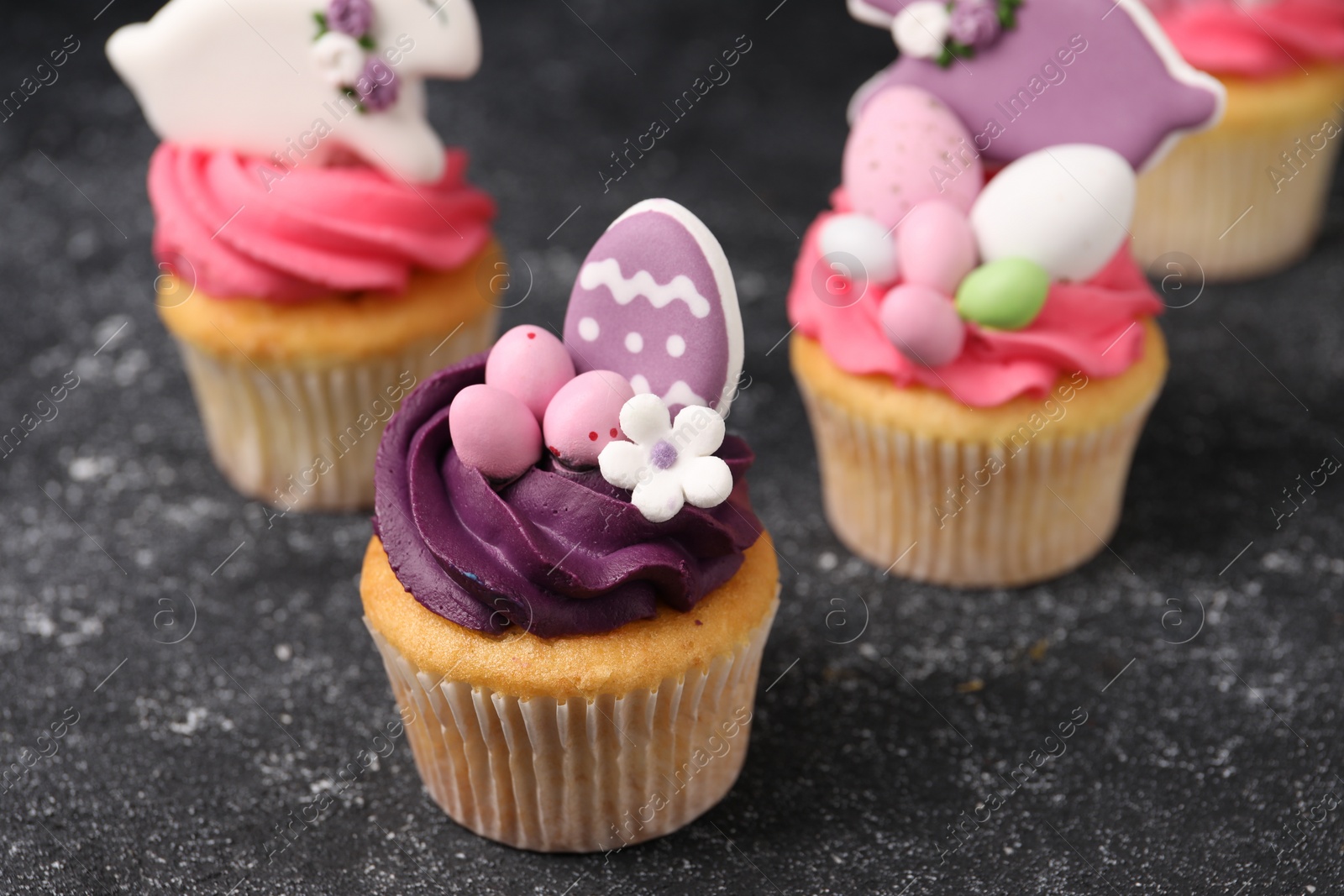 Photo of Tasty decorated Easter cupcakes on grey table, closeup