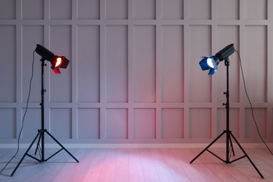 Photo of Bright red and blue spotlights near wall indoors, space for text