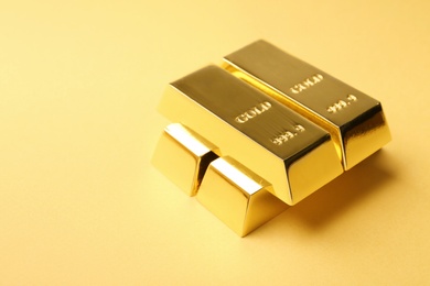 Photo of Precious shiny gold bars on color background. Space for text
