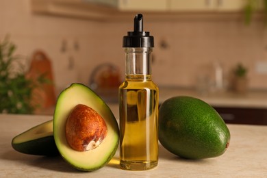 Photo of Fresh avocados and cooking oil on beige marble table in kitchen