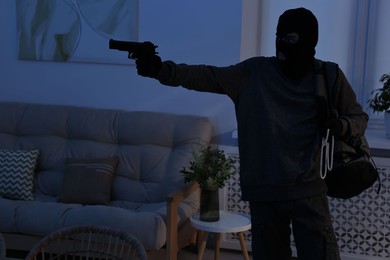 Photo of Thief with gun stealing jewels in foreign house. Burglary