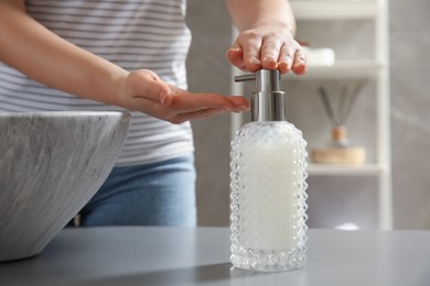 Photo of Woman washing hands with liquid soap in bathroom, closeup