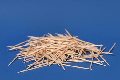 Photo of Pile of wooden toothpicks on blue background
