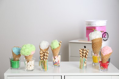 Photo of Cotton candy in waffle cones and other sweets on table in room