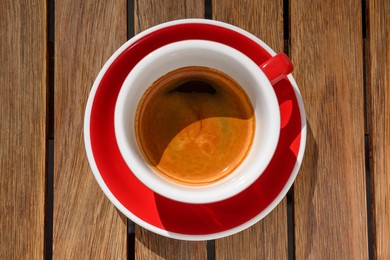 Photo of Cup of aromatic hot coffee on wooden table, top view