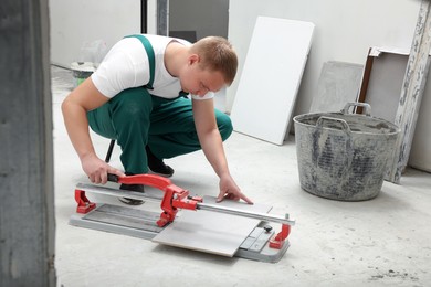 Photo of Worker using manual tile cutter in room