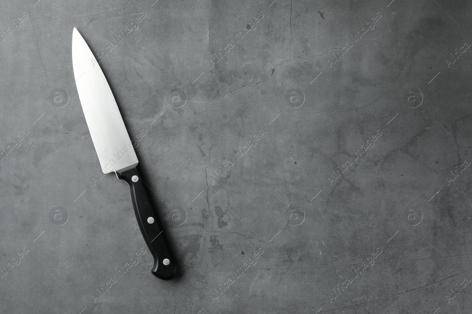 Photo of One knife on grey textured table, top view. Space for text