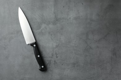 Photo of One knife on grey textured table, top view. Space for text