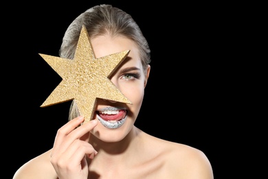 Photo of Beautiful young model with silver lips makeup and star on black background