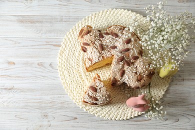 Photo of Delicious Italian Easter dove cake (traditional Colomba di Pasqua) and festive decor on white wooden table, top view. Space for text