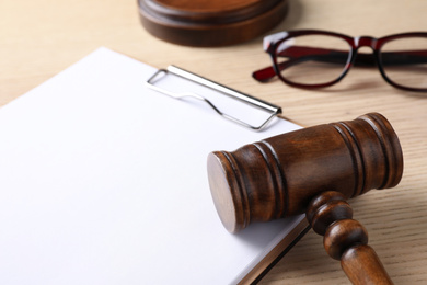 Photo of Clipboard with words DOMESTIC VIOLENCE and gavel on wooden table, closeup