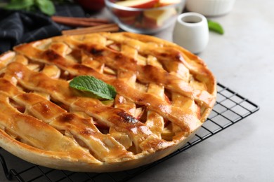 Photo of Fresh traditional apple pie with mint on light grey table, closeup
