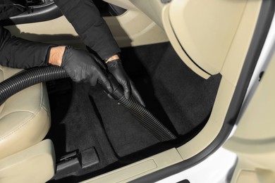 Photo of Man cleaning auto carpet with vacuum cleaner at car wash, closeup