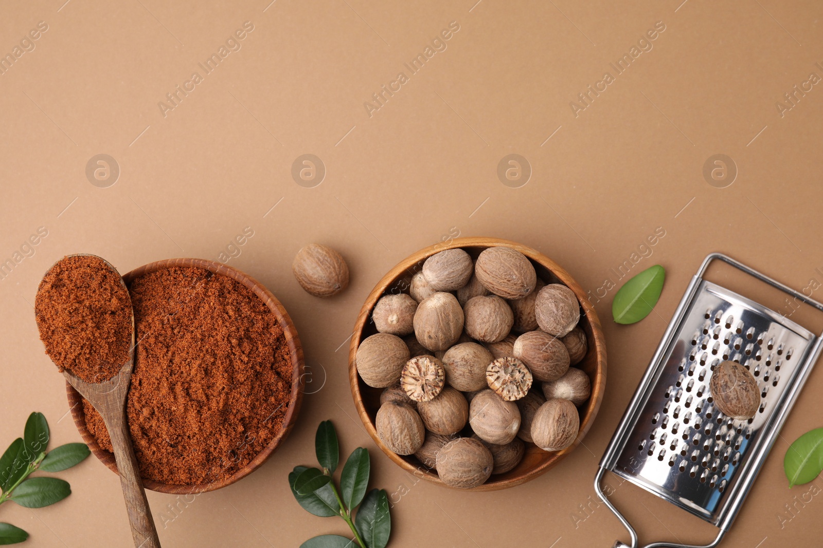 Photo of Flat lay composition with nutmegs on light brown background. Space for text